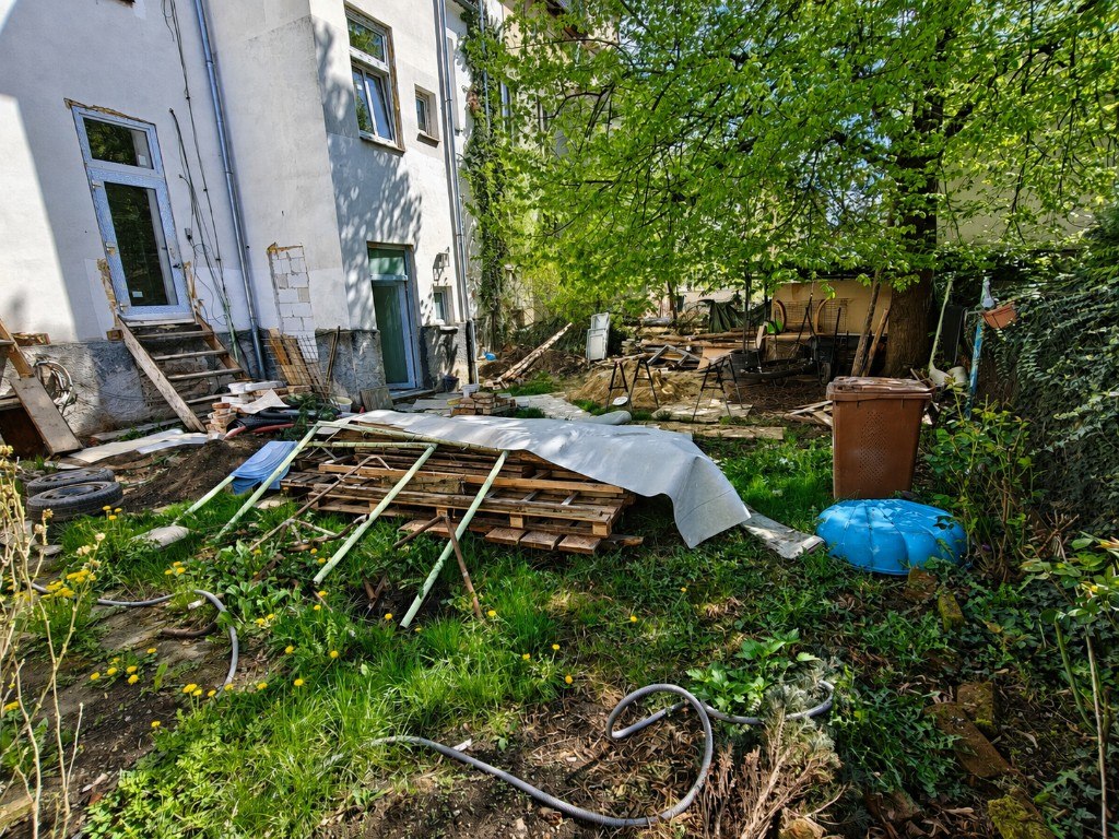 Pozemek před úpravou — suť, palety a rozestavěný dvůr